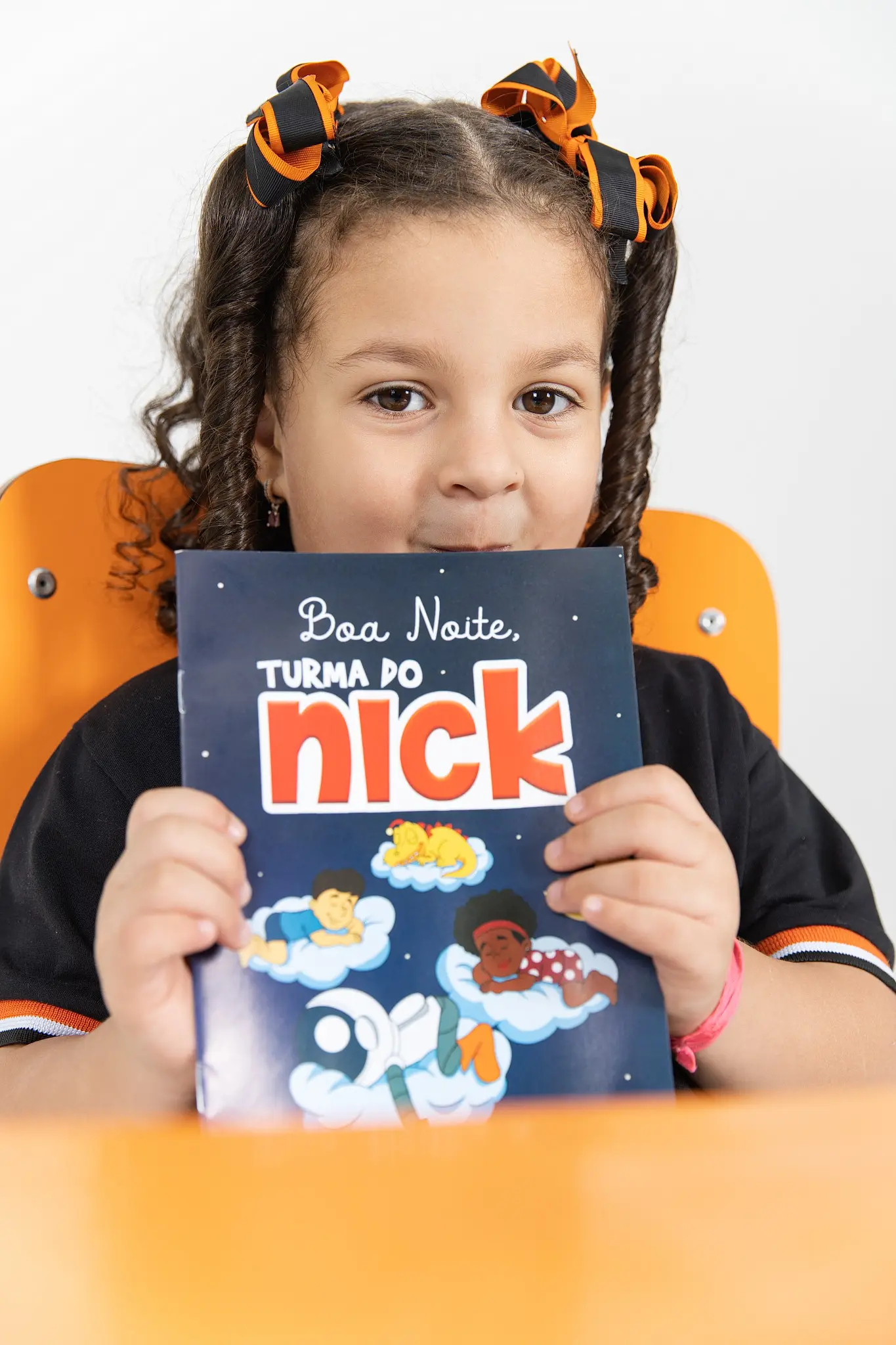 Menina sorrindo atrás do livro Boa Noite, Turma do Nick
