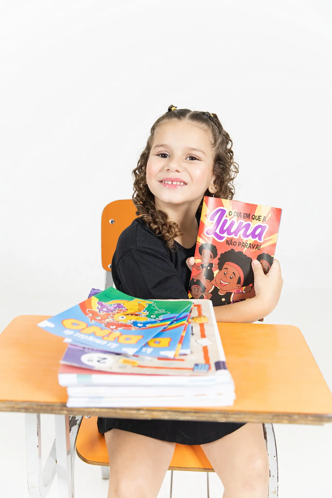Menina na carteira com o livro da Luna e outros livros