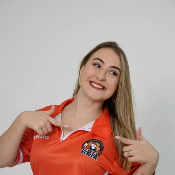 Integrante da direção do Riachuelo sorrindo e apontando para o escudo dos Crias na camisa