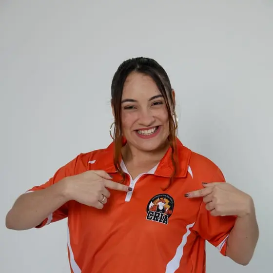 Integrante da direção do Riachuelo sorrindo e apontando para o escudo dos Crias na camisa