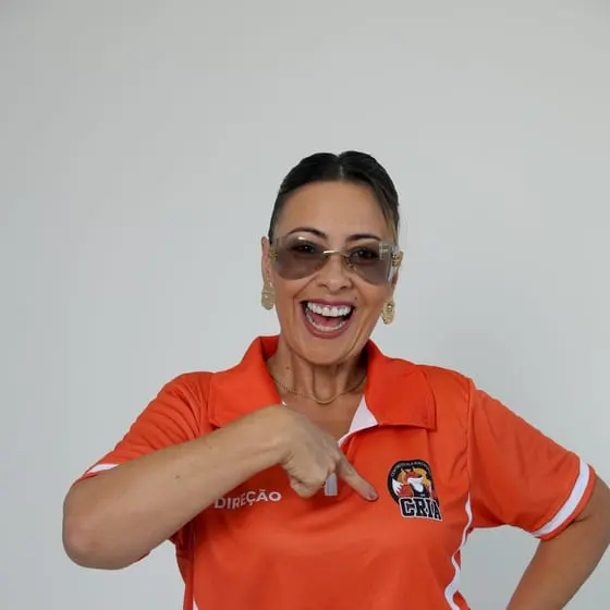 Integrante da direção do Riachuelo sorrindo e apontando para o escudo dos Crias na camisa