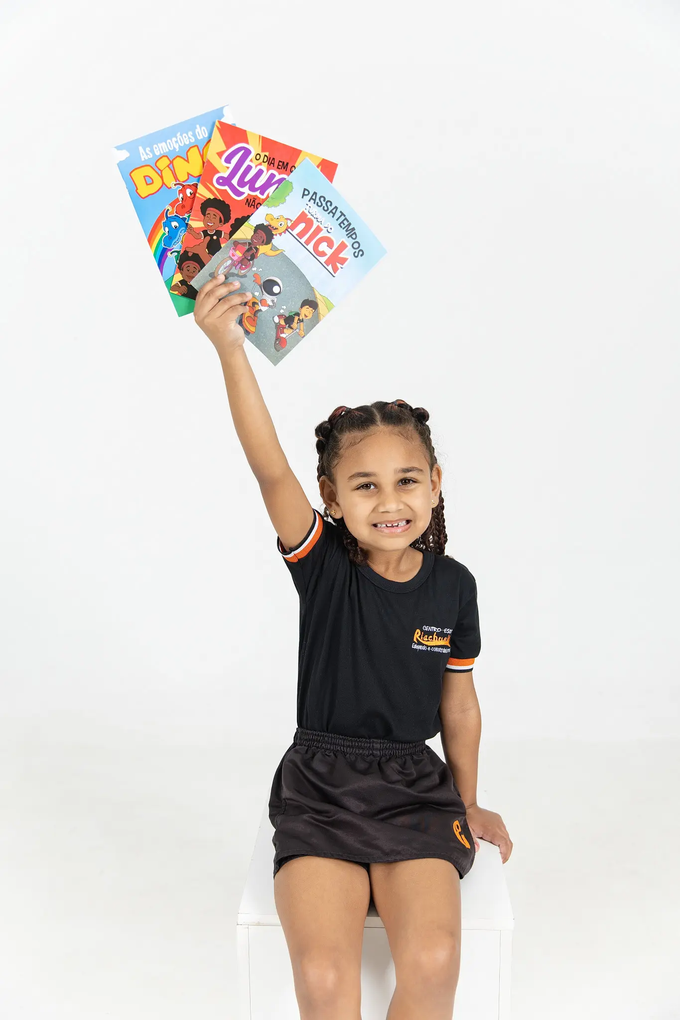 Menina levantando três livros da Turma do Nick no ar