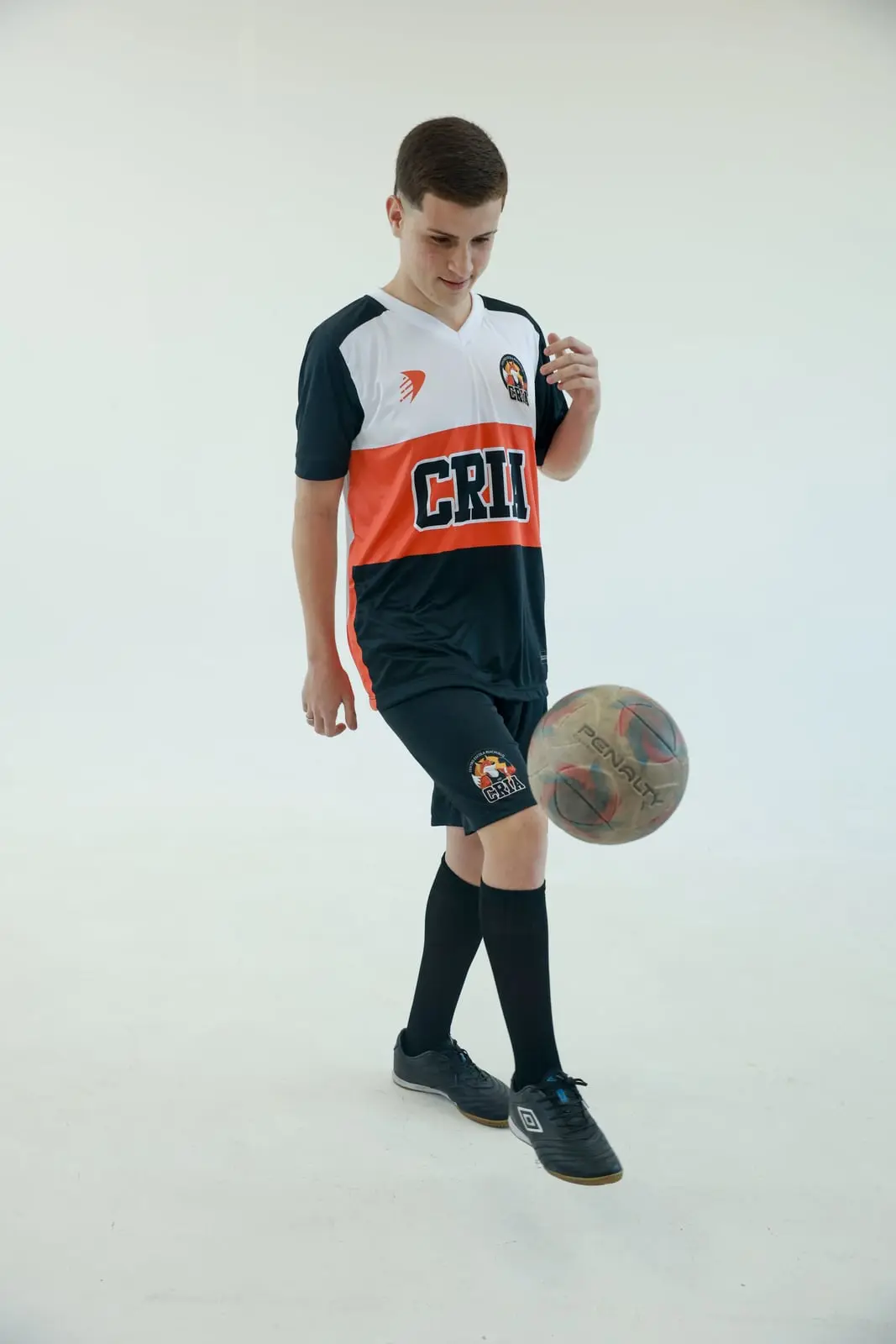 Atleta dos Crias com a camisa preta e laranja dominando a bola