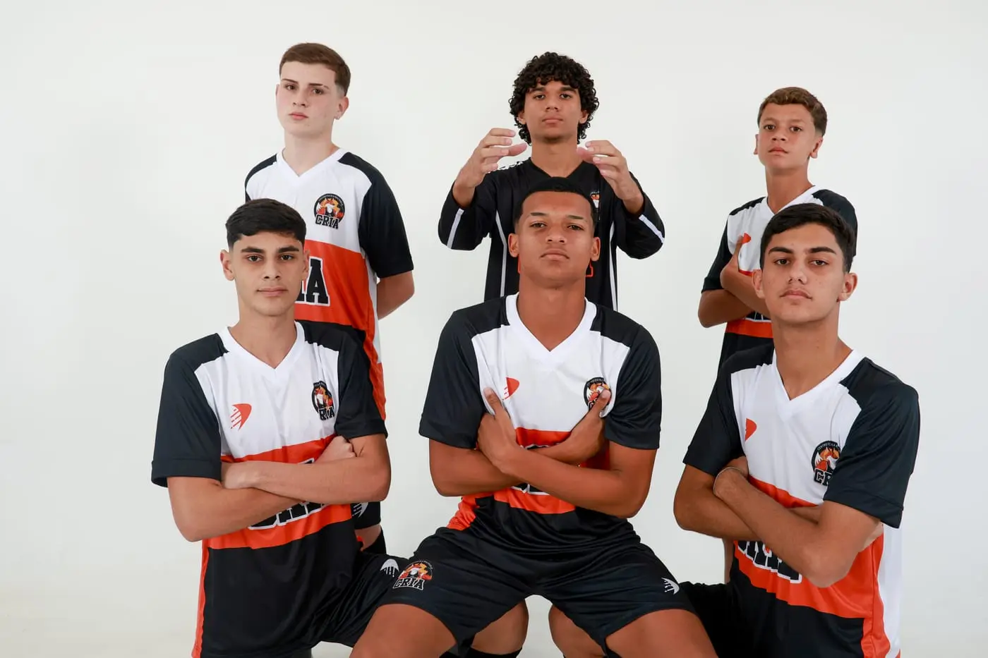 Atletas dos Crias de braços cruzados com a camisa preta e laranja